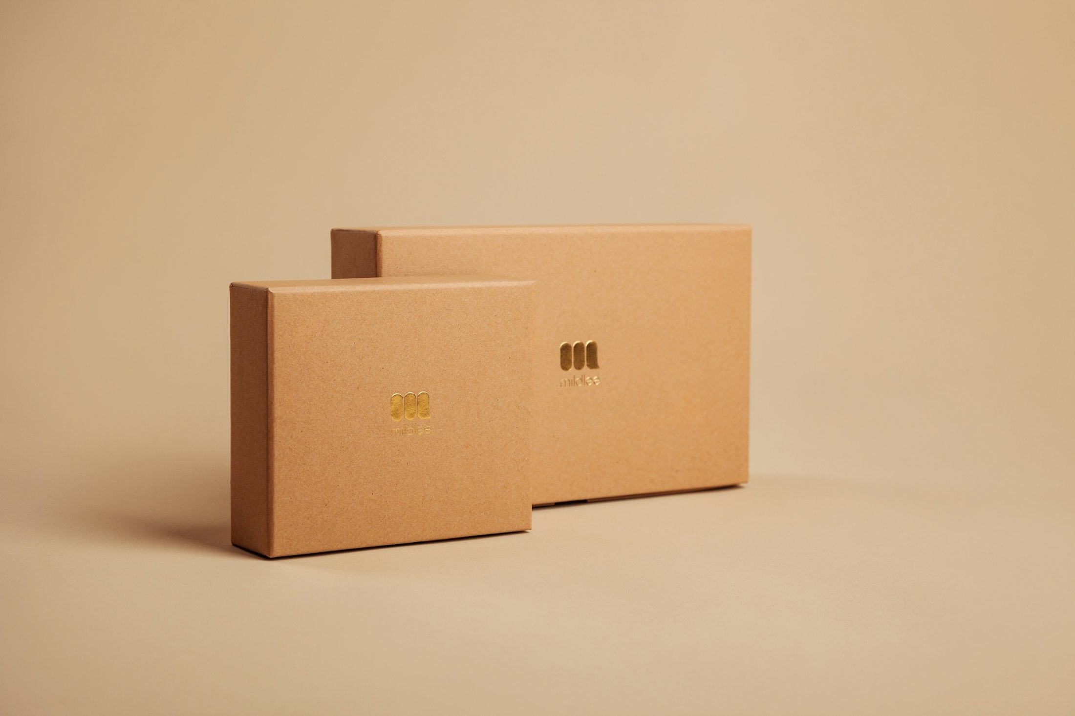 Two sand-coloured rigid boxes with a small foil emblem