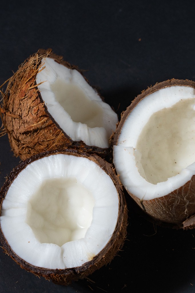 Three halved coconuts on a dark ground