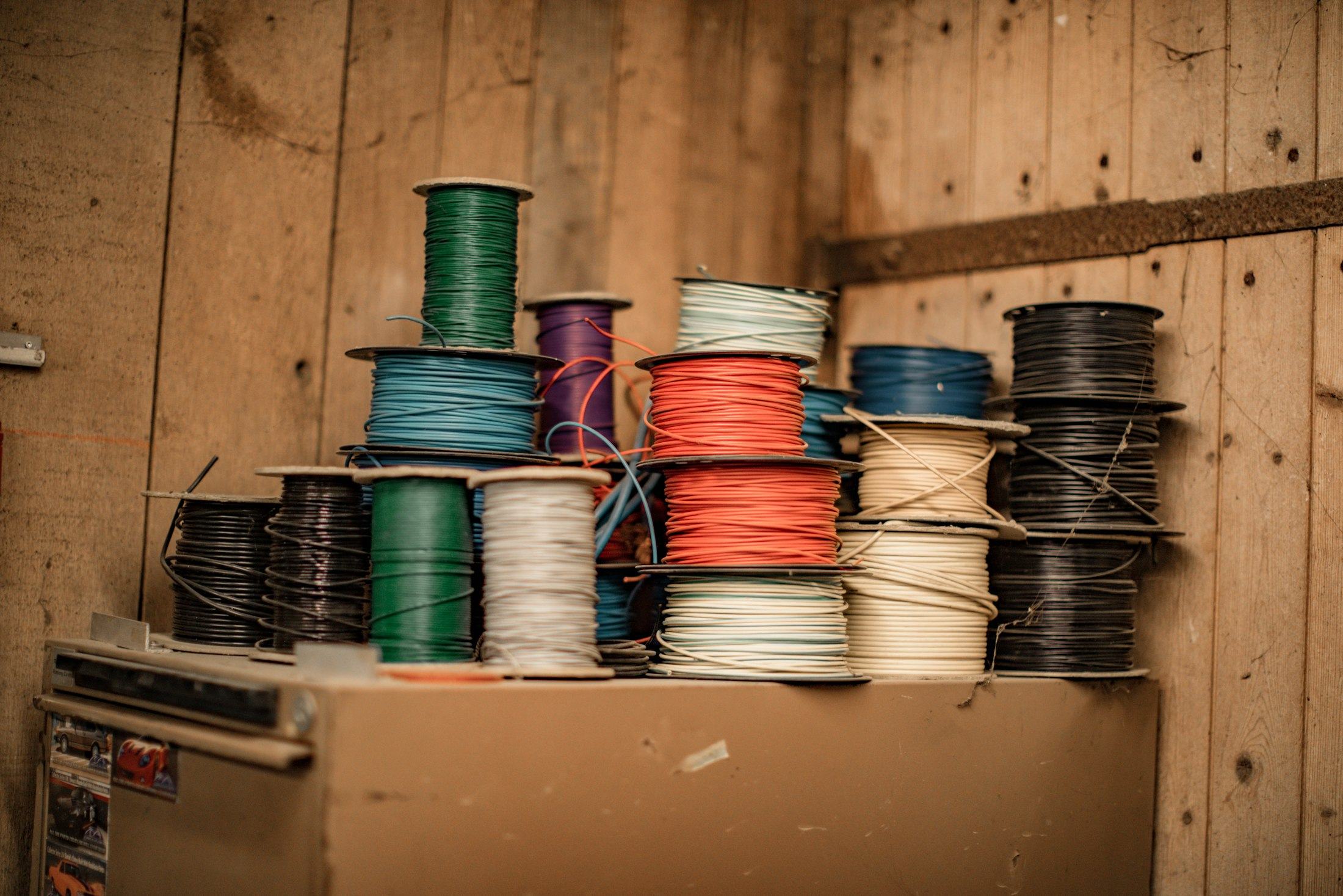 Spools of coloured wire on a wooden shelf